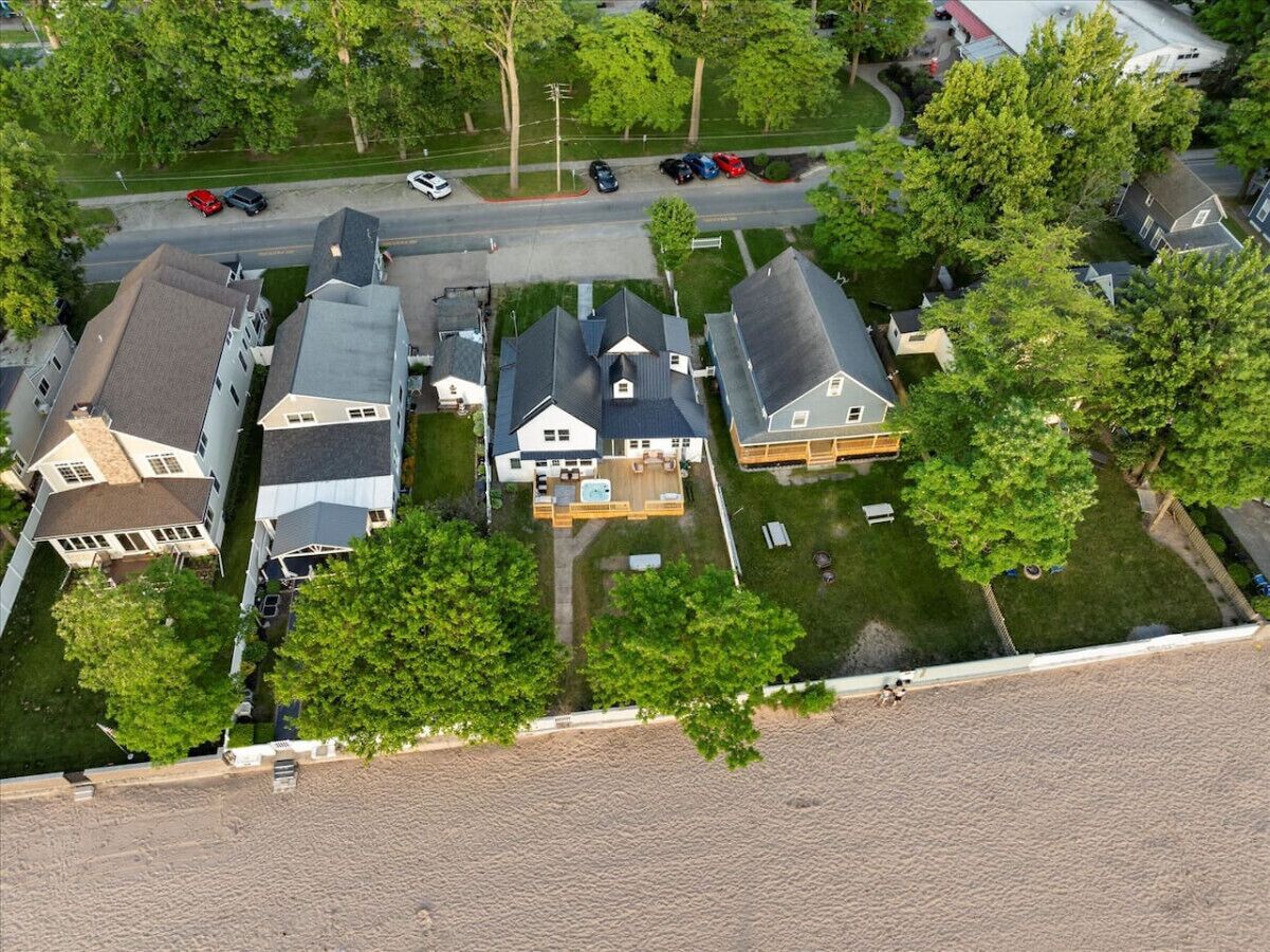 An aerial view of a residential area with houses, a road, and parked cars.