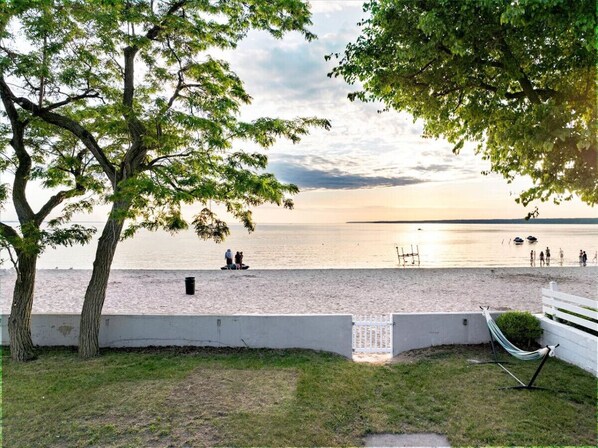 A beach view with a white fence, a hammock, and a tree.