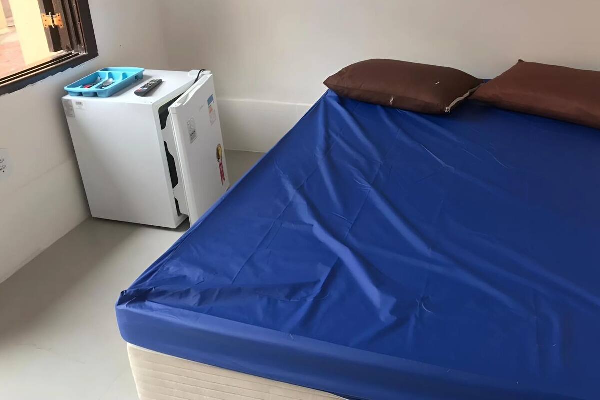 Een kleine kamer met een bed, een witte verwarming en een raam.