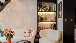 A modern living room with a staircase, a bookshelf, and a coffee table. - Contemporary Excellence, by Veeve (Paris)