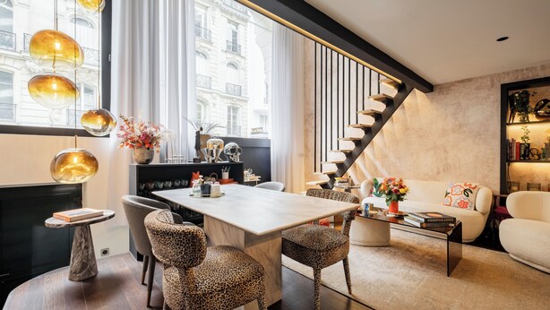 A modern living room with a dining area, a staircase, and a view of a building through large windows. - Contemporary Excellence, by Veeve (Paris)