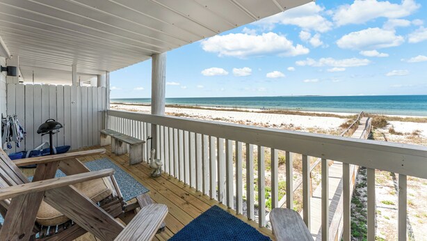 A covered deck with a view of the beach, wooden furniture, and a railing. - Oceanfront Condo | Couples | Cozy (Port St. Joe)