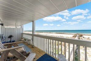 A covered deck with a view of the beach, wooden furniture, and a railing. - Oceanfront Condo | Couples | Cozy (Port St. Joe)
