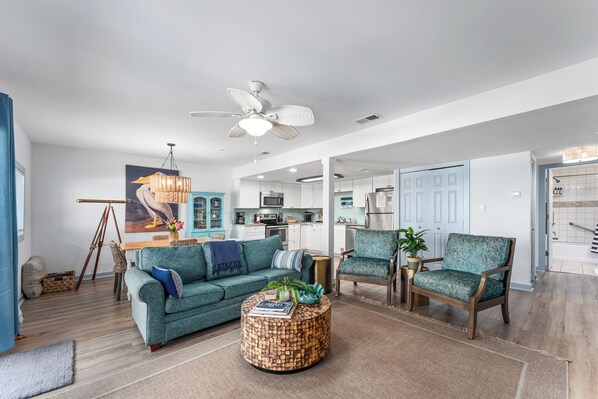 A modern living room with a sofa, chairs, a round coffee table, and a ceiling fan. - Oceanfront Condo | Couples | Cozy (Port St. Joe)