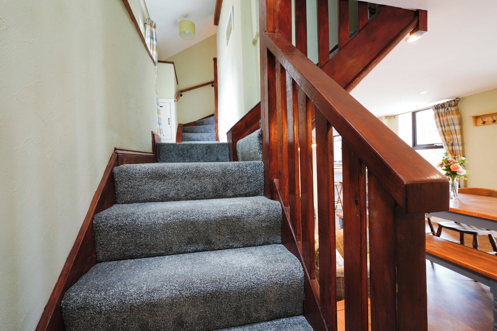 A staircase with wooden railings and carpeted steps leading to a dining area.