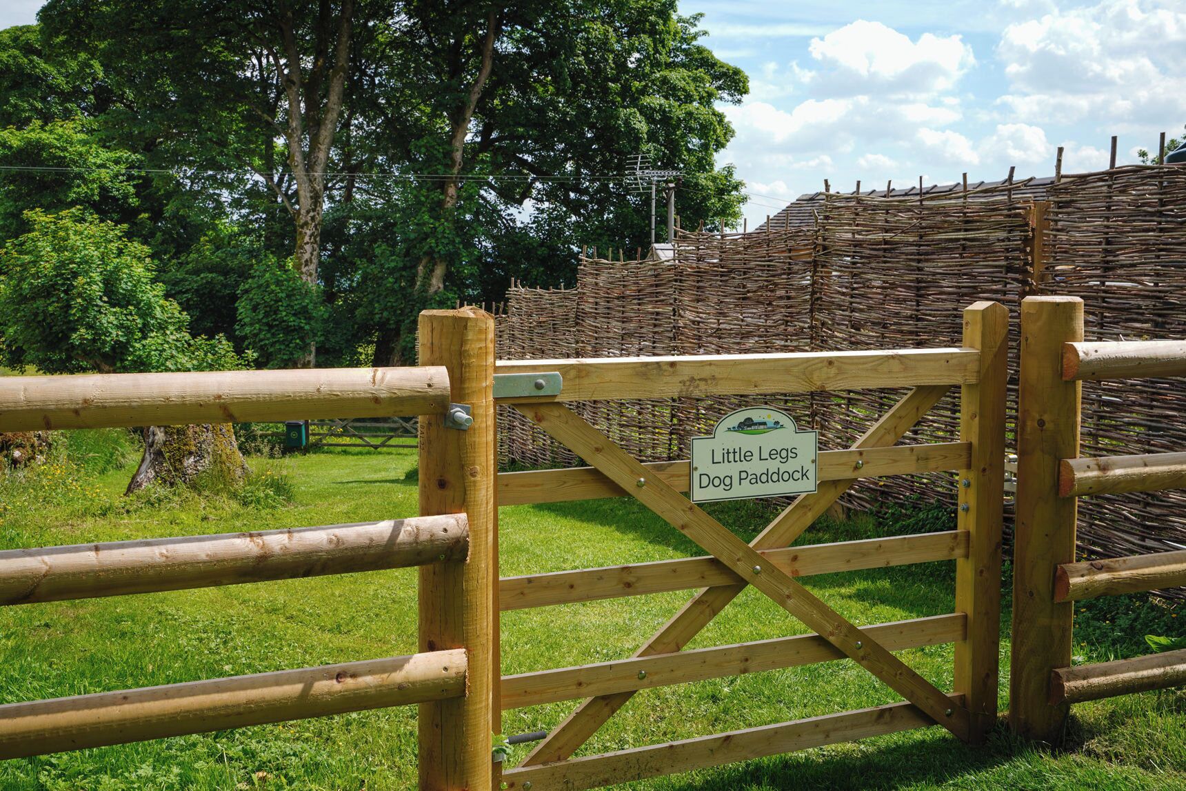 A wooden gate with a sign reading "Little Legs Dog Paddock".