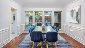 Een formele eetzaal met een lange tafel, blauwe stoelen en een blauw tapijt.