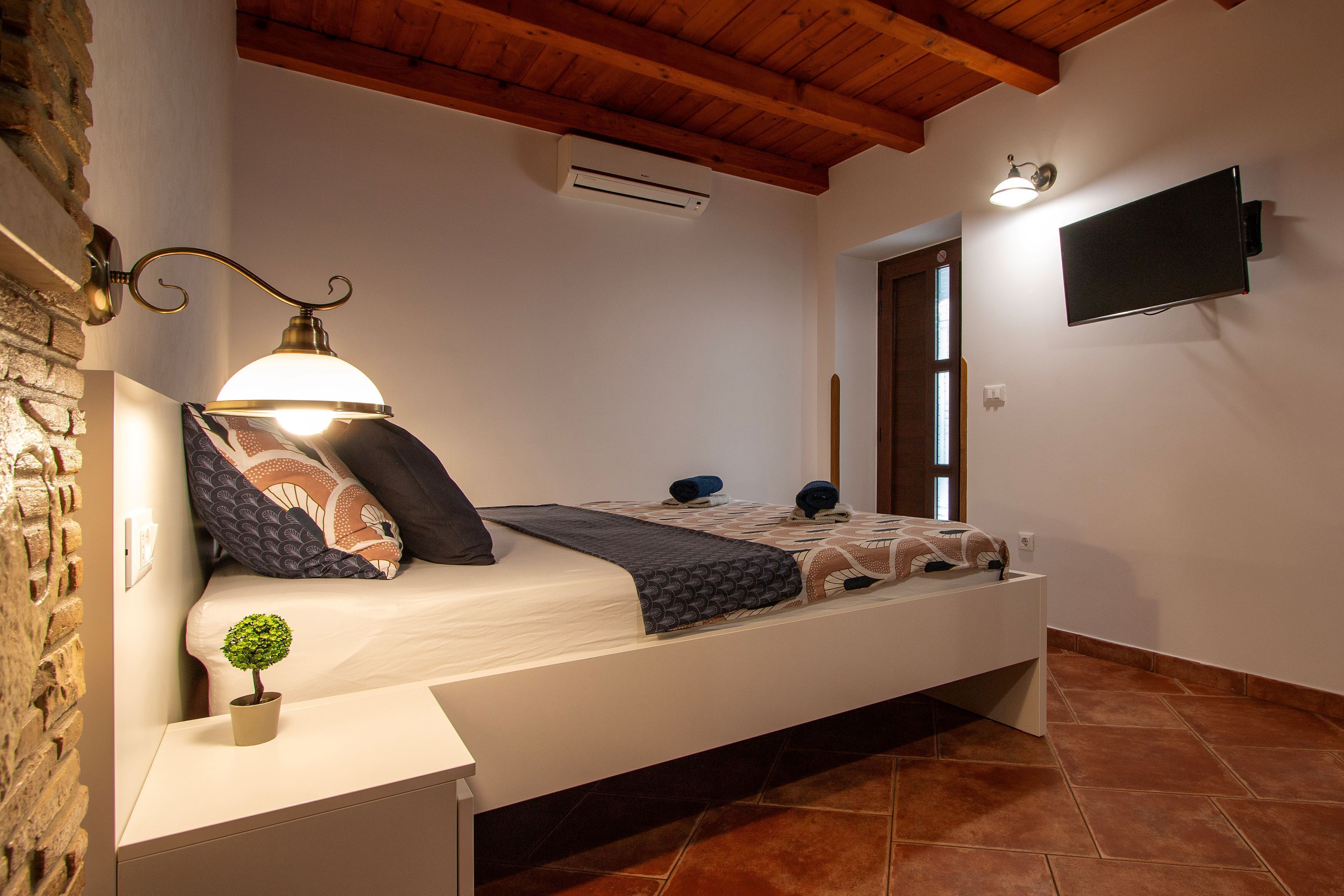 Camera da letto con un letto, una lampada da comodino, condizionatore d'aria, televisione e una piccola pianta in vaso.