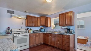 A kitchen with wooden cabinets, a white stove, granite countertops, and a wooden floor. - Sonoran Velo Summary: (Tucson)
