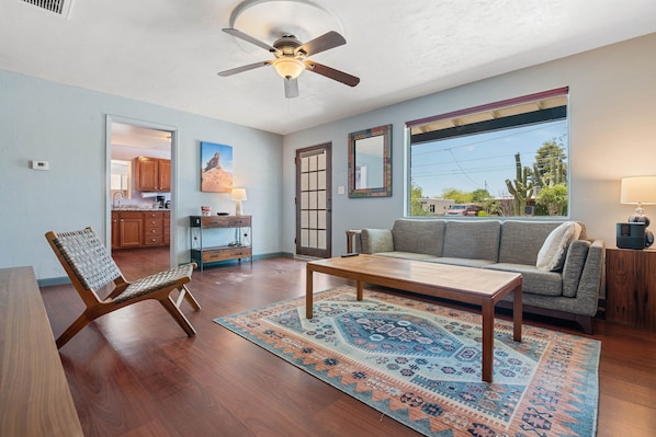 A spacious living room with a ceiling fan, a sofa, a coffee table, and a patterned rug.