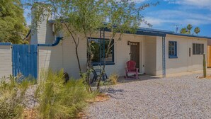 A small, single-story building with a blue door and a red chair outside. - Sonoran Velo Summary: (Tucson)