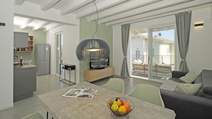 A modern living area with a dining table, a sofa, and a kitchen in the background.