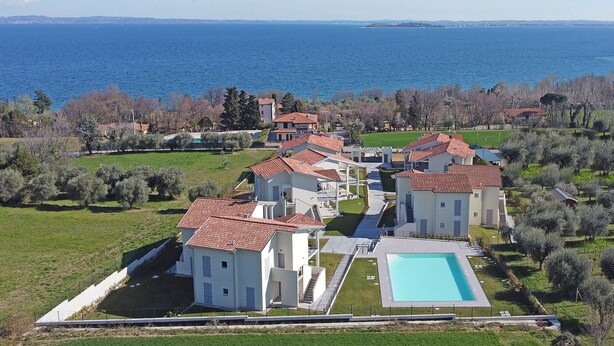 A coastal property with multiple villas, a swimming pool, and a view of the sea.