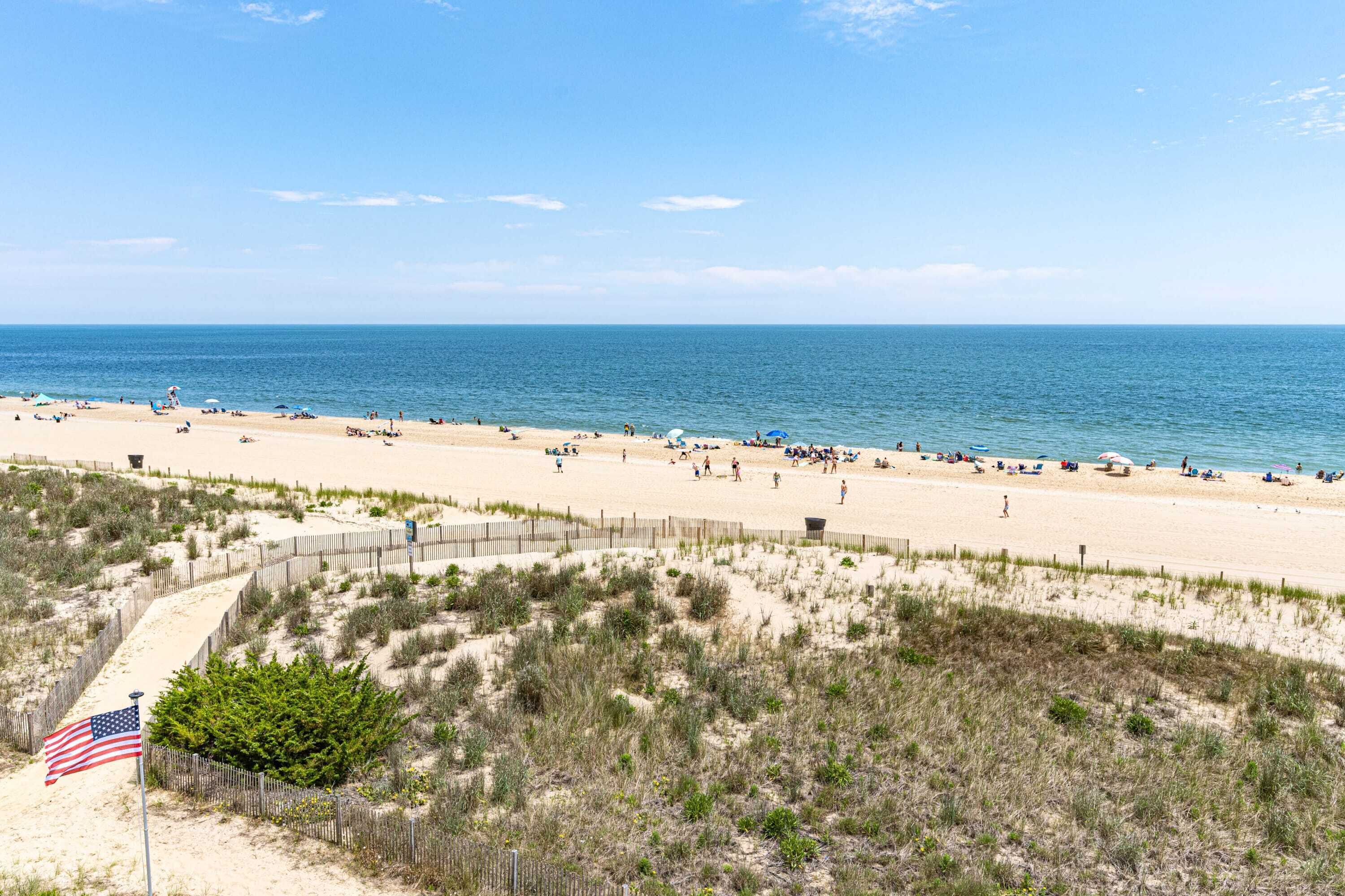 A beach with a sandy shore, a wooden fence, and an American flag.