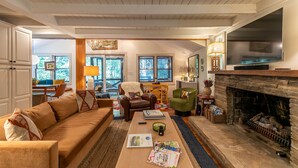 A cozy living room with a fireplace, a sofa, a coffee table with magazines, and a television. - Anglers Cottage (Blowing Rock)