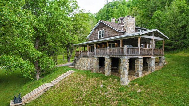 A rustic cabin with a stone foundation, wooden deck, and a covered porch. - Orchard House (Banner Elk)