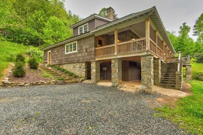 A two-story house with a stone foundation, wooden deck, and a stone staircase leading to the entrance. - Orchard House (Banner Elk)