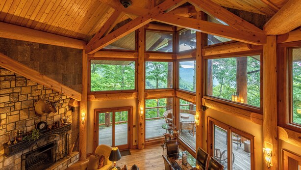 A spacious lodge with a stone fireplace, large windows, and a wooden deck. - Big Bear Lodge at Eagles Nest (Banner Elk)