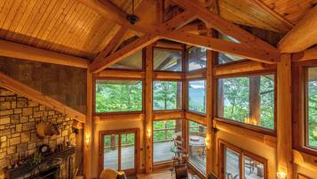 A spacious lodge with a stone fireplace, large windows, and a wooden deck.