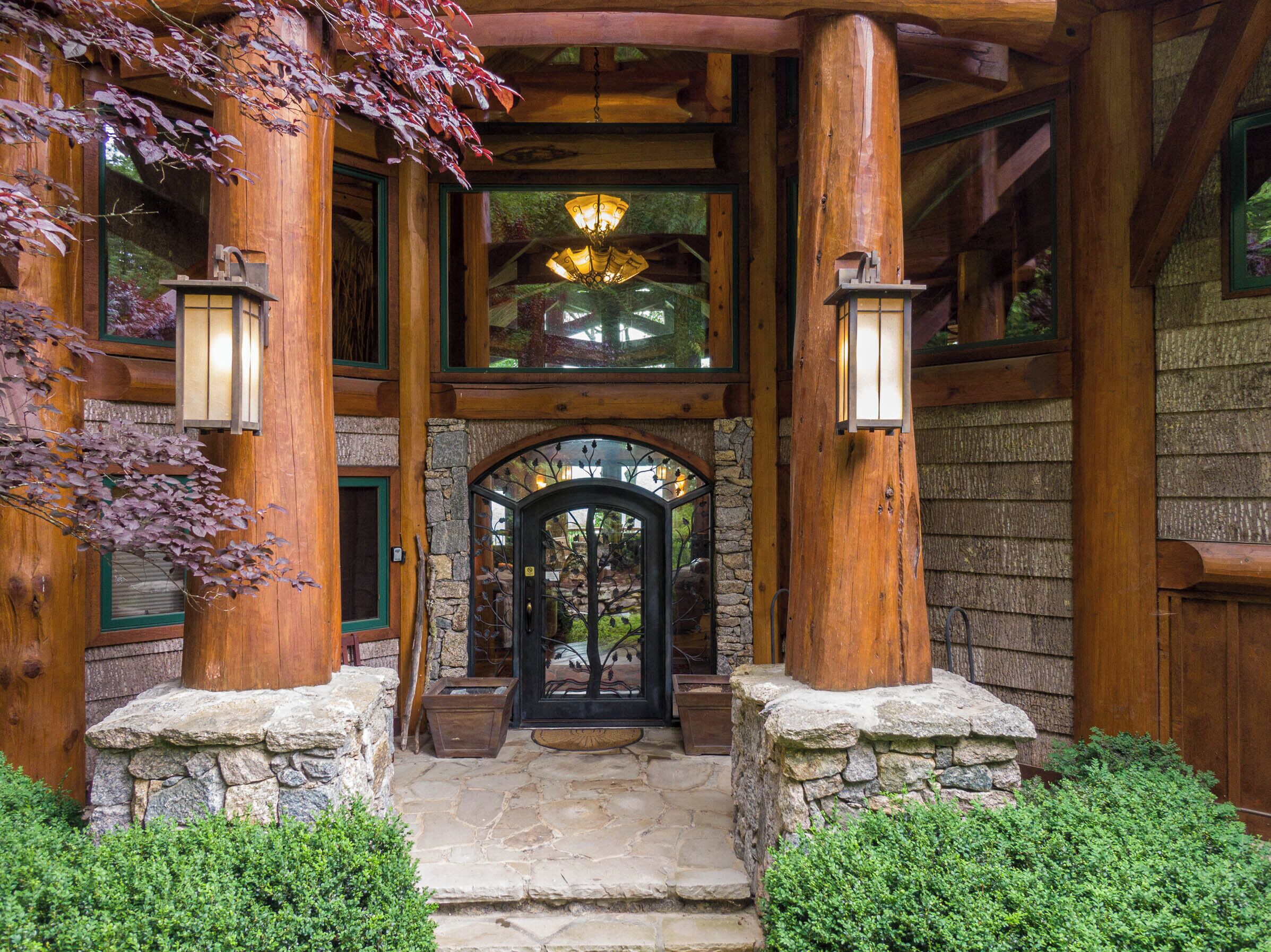 A rustic wooden building with a stone entrance, wooden columns, and a glass door.