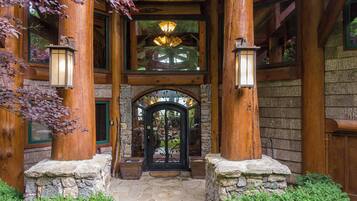 A rustic wooden building with a stone entrance, wooden columns, and a glass door.