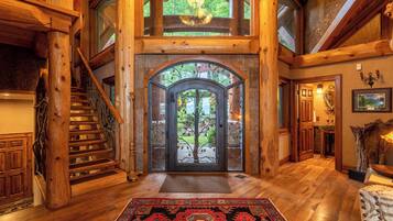 A wooden staircase leading to a glass door with a tree view, a rug, and a wooden floor.