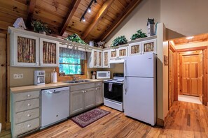 A kitchen with wooden cabinets, a refrigerator, a microwave, and a dishwasher. - Yearling (Banner Elk)