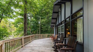 A wooden deck with chairs and a table, surrounded by trees. - Rivers Edge in Todd (Todd)