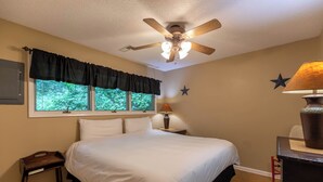 A bedroom with a bed, a ceiling fan, a window with curtains, a nightstand with a lamp, and a dresser. - Rivers Edge in Todd (Todd)
