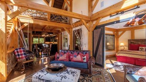 A spacious room with a wooden ceiling, a leather sofa with red and white pillows, a patterned rug, and a wooden rocking chair. - Rustic Cedar Rock Townhome at Eagles (Banner Elk)
