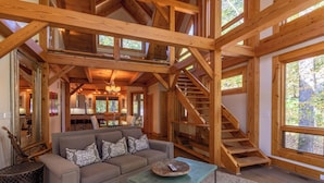 A spacious living area with a wooden staircase, a sofa with patterned cushions, and a coffee table. - Modern Cedar Rock Townhome at Eagles (Banner Elk)