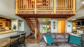 A spacious living area with a high ceiling, a wooden staircase, and a cozy seating area with a sofa and chairs. - Mount Ever-Rest (Banner Elk)