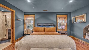 A bedroom with a large bed, wooden headboard, two bedside tables, and a window with a view. - Snowflake River Ridge at Eagles Nest (Banner Elk)