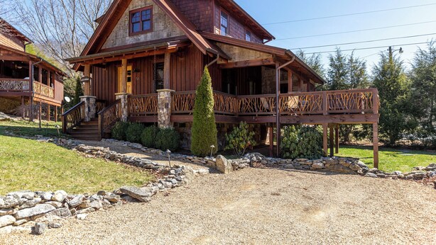 A wooden cabin with a porch, stone pathway, and a small garden. - Snowflake River Ridge at Eagles Nest (Banner Elk)