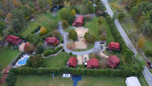 An aerial view of a residential area with multiple houses, a swimming pool, and a road. - Snowflake River Ridge at Eagles Nest (Banner Elk)