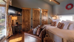 A bedroom with a bed, a TV, wooden doors, a window with curtains, and a ceiling fan. - Hilltop Hideout at Eagles Nest (Banner Elk)
