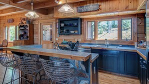 A rustic cabin interior with a large stone island, wooden walls, and a view of the outdoors. - Boles Lodge (Boone)