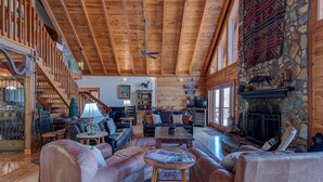 A spacious living room with wooden beams, a stone fireplace, and a cozy seating area. - Boles Lodge (Boone)