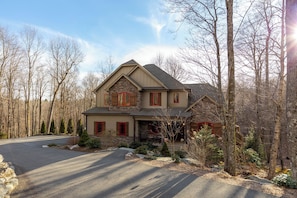 A two-story house with a stone facade, red shutters, and a stone chimney. - Fern Ridge Lodge at Sweetgrass (Blowing Rock)