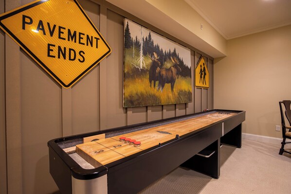 A pool table in a room with a 'Pavement Ends' sign and a wildlife painting on the wall. - Fern Ridge Lodge at Sweetgrass (Blowing Rock)