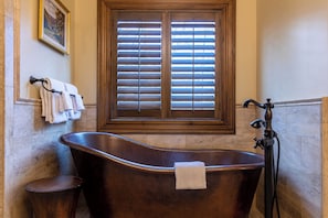 A bathroom with a freestanding bathtub, a window with blinds, and a towel rack with towels. - Fern Ridge Lodge at Sweetgrass (Blowing Rock)