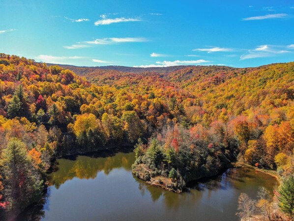 Un paysage paisible avec un lac entouré d’arbres aux couleurs automnales et une chaîne de montagnes lointaine.