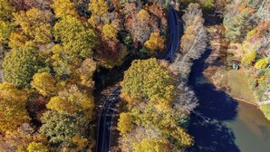 An aerial view of a winding road through a forested area with autumn foliage. - Lake Overlook (Banner Elk)
