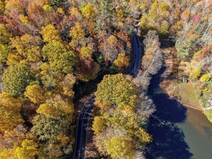 Vue aérienne d’une route sinueuse traversant une zone boisée aux couleurs automnales.