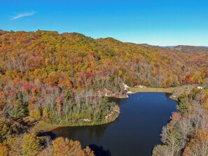 Un lac entouré d’arbres et de collines aux couleurs automnales.