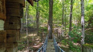 A wooden bridge in a forest with a rustic cabin on the left. - Matney Ridge Estate (Banner Elk)