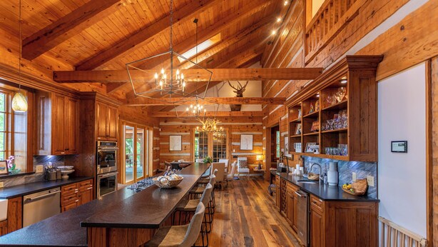 A spacious kitchen with wooden cabinets, a long island with bar stools, and a chandelier. - Matney Ridge Estate (Banner Elk)
