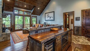 Una cocina amplia con techo de madera, ventanas grandes y chimenea de piedra.