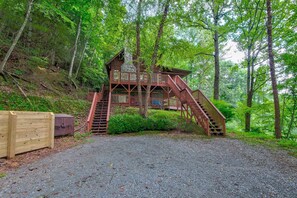 A wooden cabin with a staircase leading to a deck, surrounded by dense forest. - St Johns Ridge (Sugar Grove)