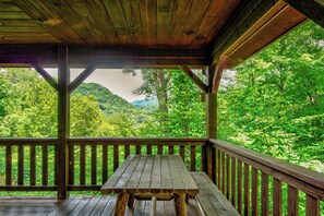 A wooden deck with a picnic table, surrounded by lush green forest and hills. - Crosswind (Vilas)